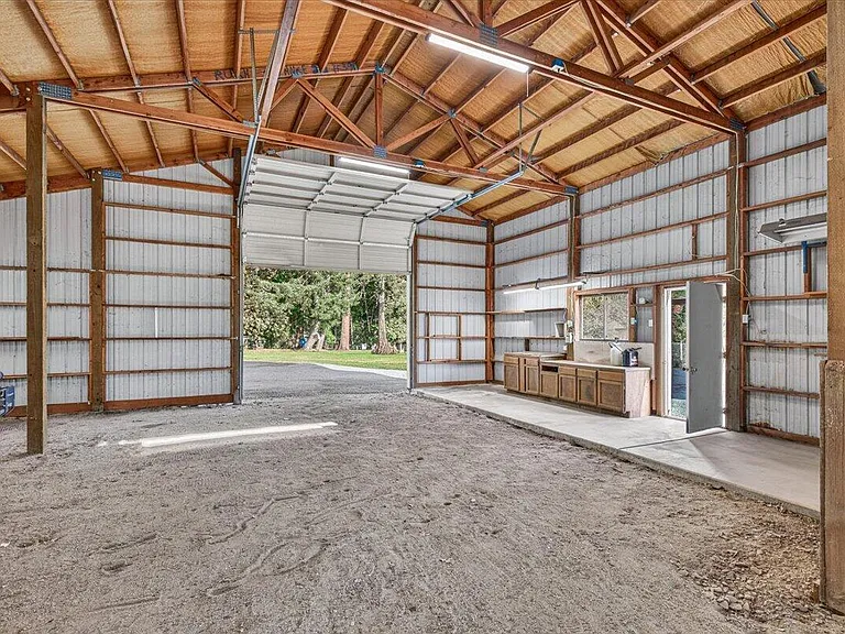 The cleared barn with its large open door, timber framing, and cabinets beneath the window