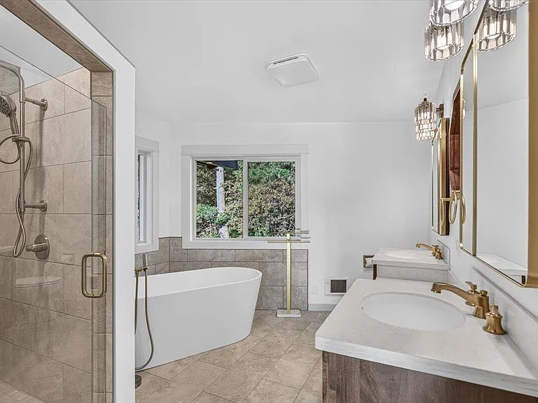 Finished bathroom with a glass shower, freestanding tub, and vanity