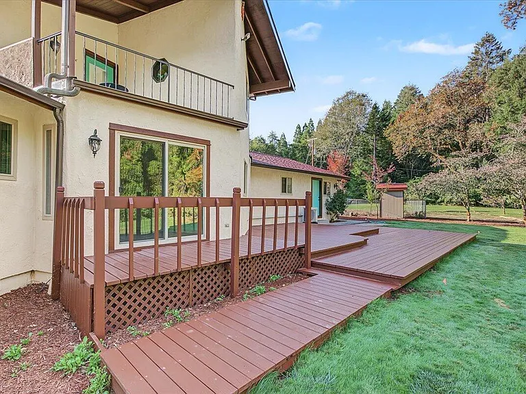 The deck outside the finished house, beside green lawn