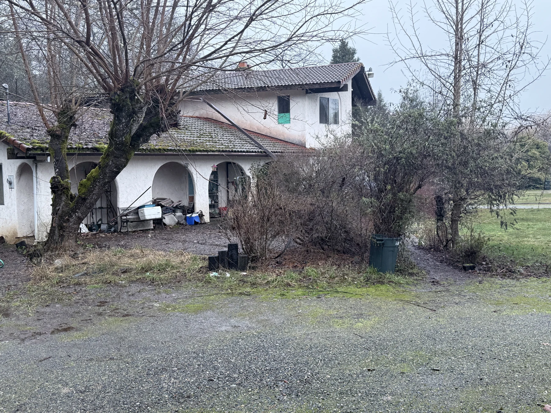 The white house before rehab, with dense vegetation around the front arches