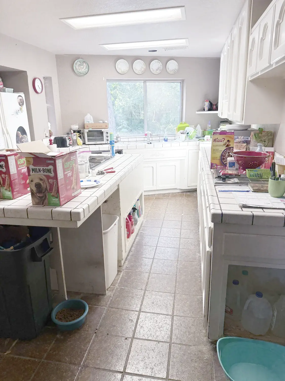 The kitchen before rehab, with tile countertops and belongings on the island