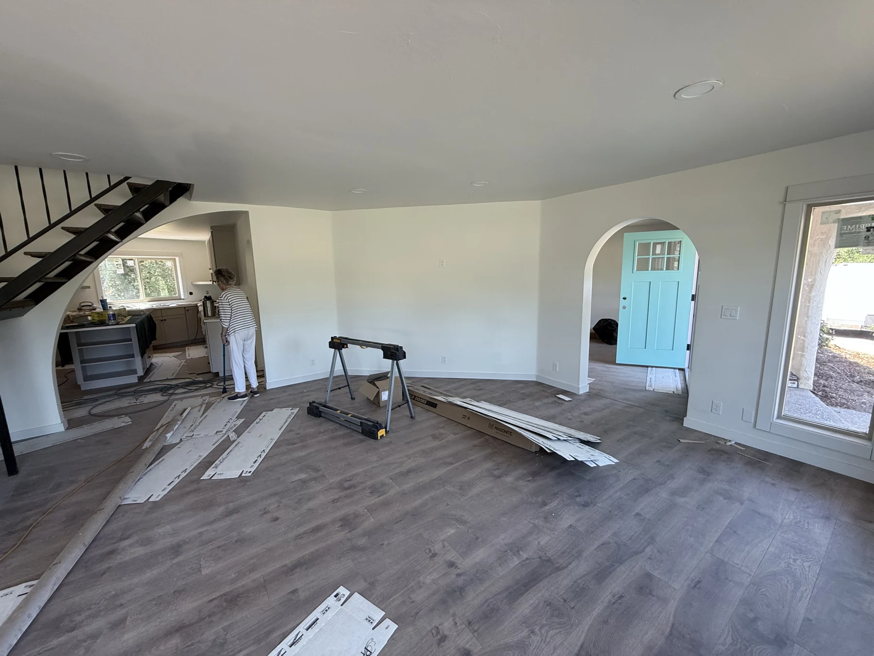 The living room during the rehab, with flooring, tools, and materials still in the room