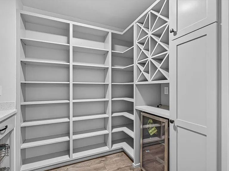 White pantry shelving with a wine rack and under-counter refrigerator